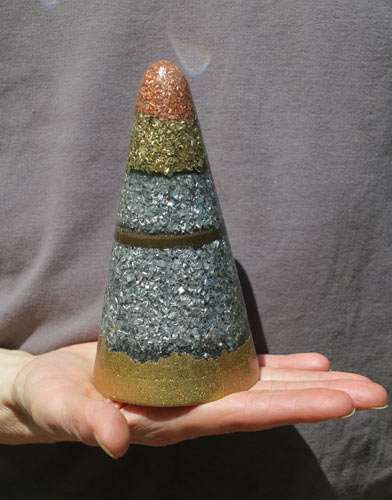 An orgonite cone composed of various metal shavings and powders.